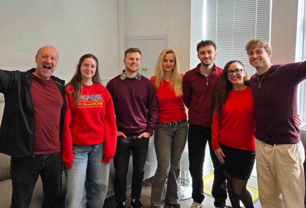 a picture of 3 women in red jumpers and 4 men in red tops standing together for a group photo